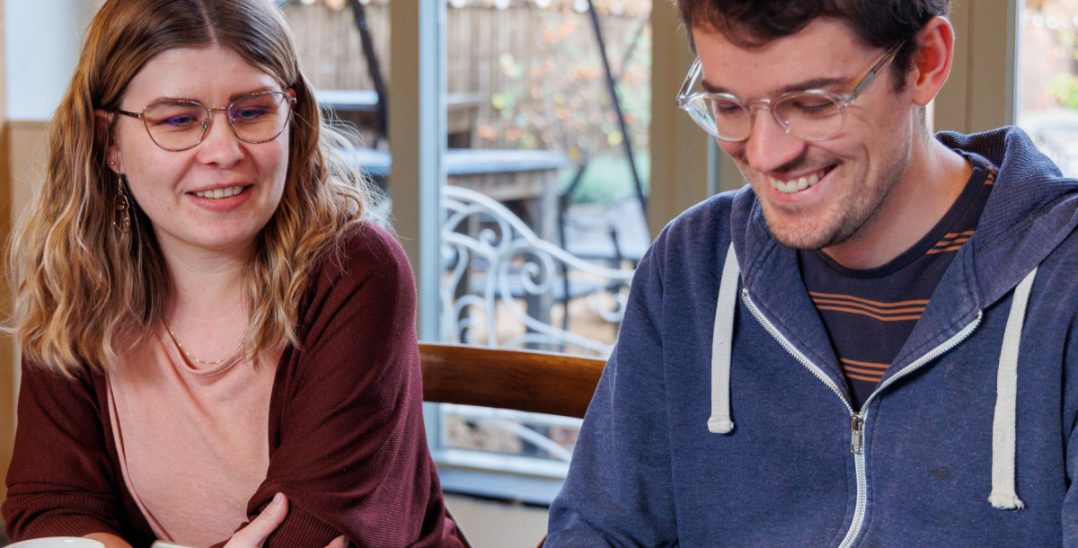 two people smiling at a laptop