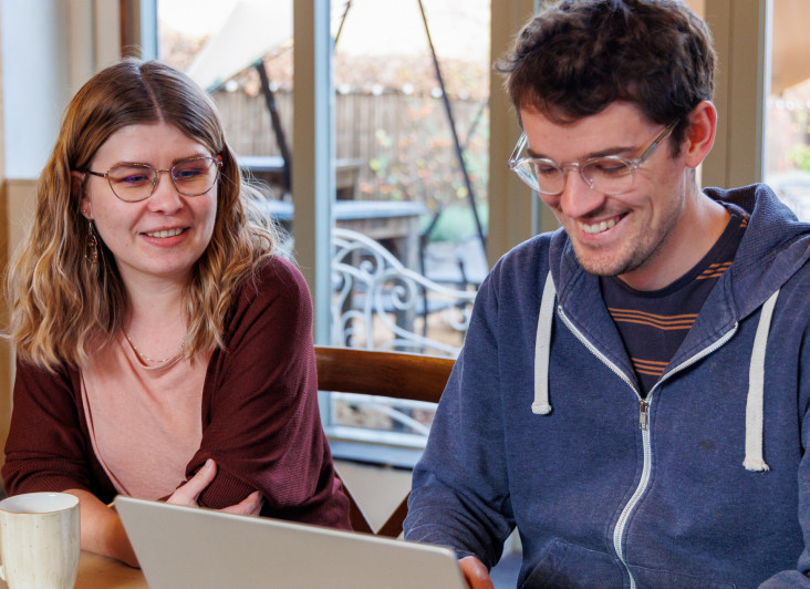 two people smiling at a laptop