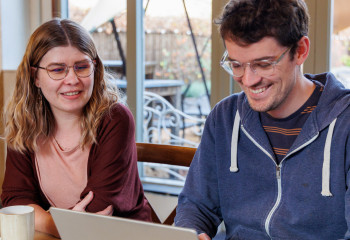 two people smiling at a laptop