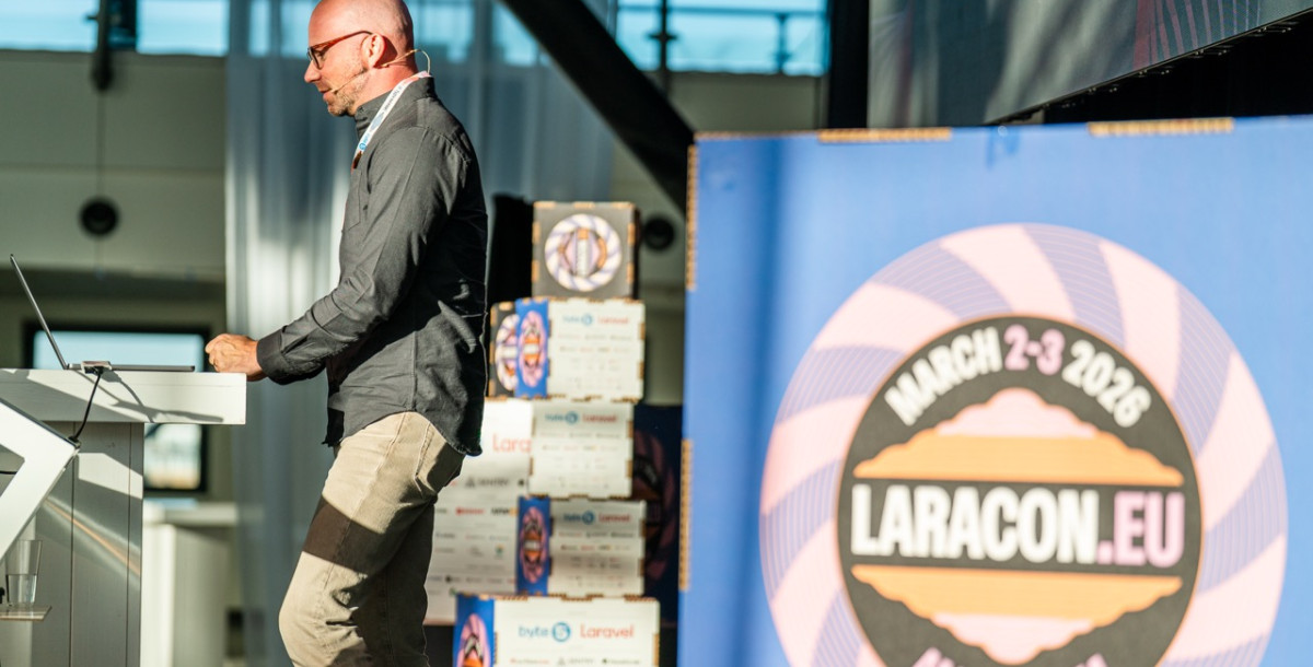 A speaker stands at a podium during a conference, engaged in a presentation. In the background, a large logo for Laracon EU features the event date and location. Bright lighting and a large screen are visible in the setting.